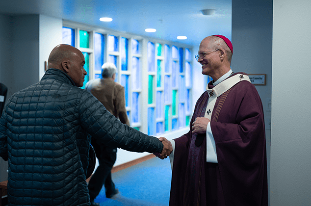 Archbishop Etienne shaking a man's hand at the 2024 Crozier Lenten Retreat